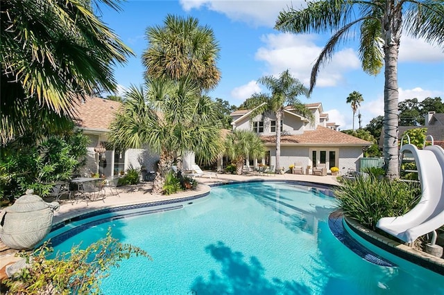 pool with a patio area, french doors, fence, and a water slide