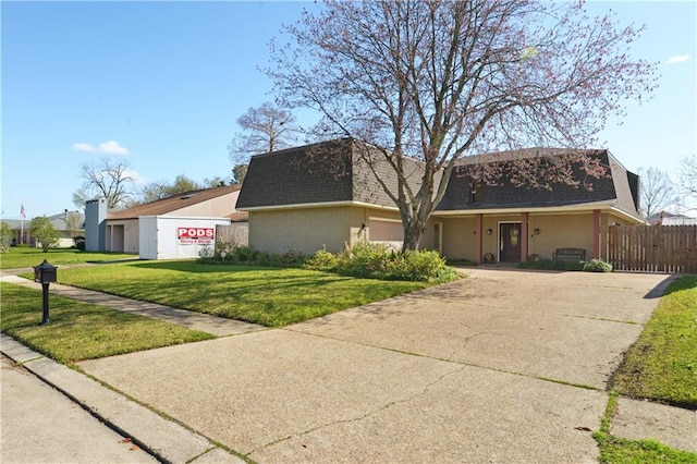 view of front facade featuring concrete driveway, a front yard, roof with shingles, mansard roof, and a garage