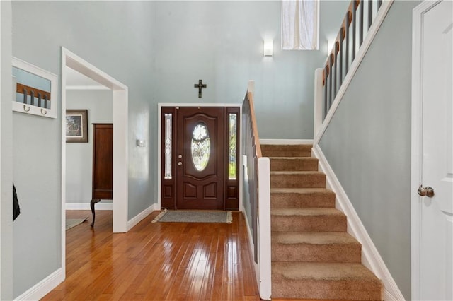 entrance foyer featuring stairway, baseboards, a high ceiling, and hardwood / wood-style floors