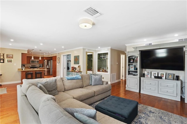 living area with visible vents, crown molding, baseboards, and wood finished floors