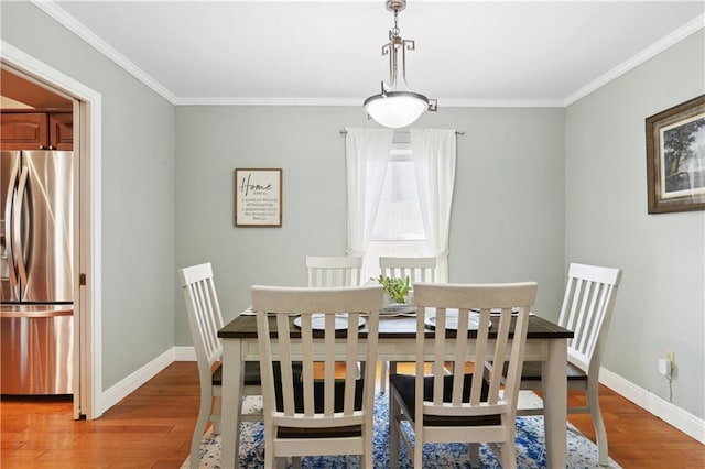 dining space with light wood-style flooring, crown molding, and baseboards