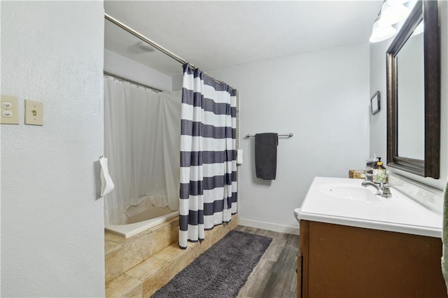 bathroom featuring a shower with shower curtain, vanity, baseboards, and wood finished floors