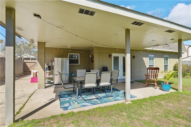 view of patio featuring french doors, fence, and visible vents