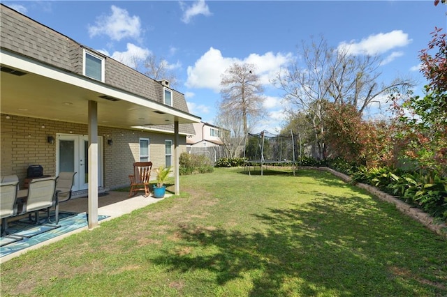 view of yard featuring a patio, a trampoline, and french doors