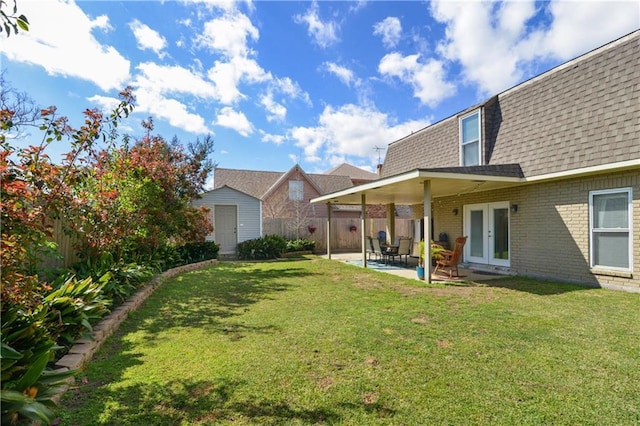 view of yard with an outbuilding, a patio, a fenced backyard, a shed, and french doors