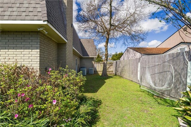 view of yard with central air condition unit and fence