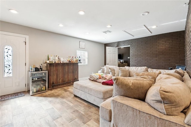 living room with light wood-type flooring, visible vents, recessed lighting, brick wall, and a dry bar