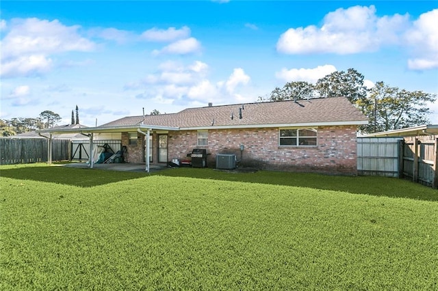 back of house with central AC, a fenced backyard, a yard, brick siding, and a patio area