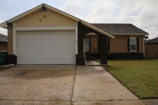 view of front of property featuring a front yard, an attached garage, and driveway
