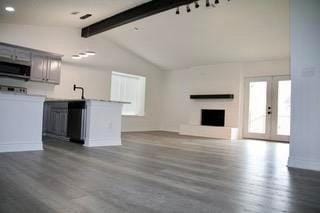 unfurnished living room with lofted ceiling with beams and dark wood-style floors