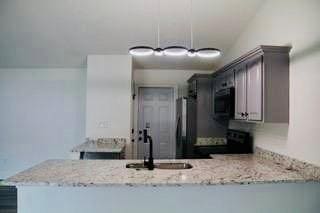 kitchen with a sink, black appliances, light stone countertops, and a peninsula