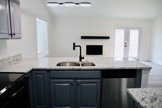 kitchen featuring a sink, light stone counters, black electric range, french doors, and a peninsula