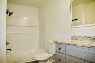 bathroom featuring toilet, vanity, and shower / tub combination