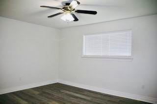 unfurnished room with a ceiling fan, baseboards, and dark wood-style flooring