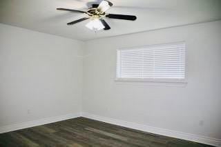 empty room featuring dark wood-style flooring, baseboards, and ceiling fan