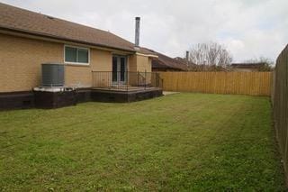 view of yard featuring a fenced backyard, a deck, and central air condition unit