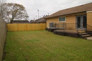 view of yard with a wooden deck, central AC, and a fenced backyard