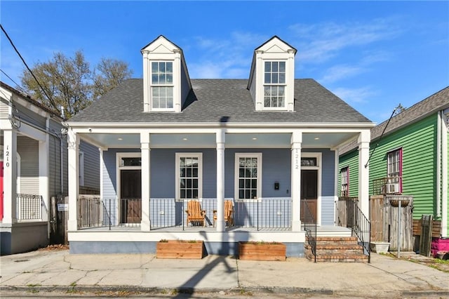 cape cod home with a porch and a shingled roof