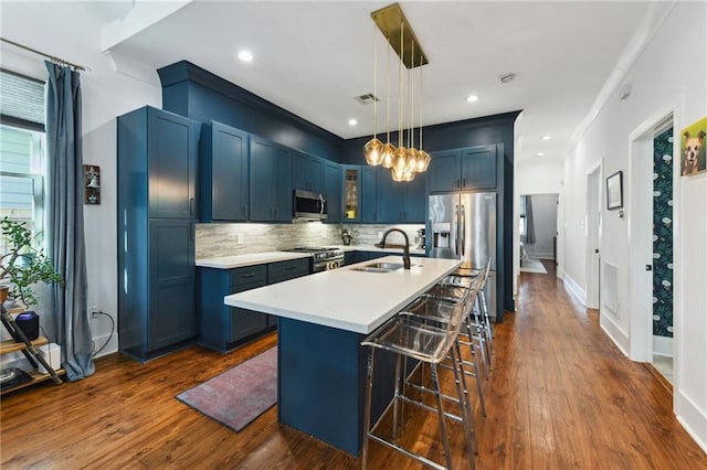 kitchen with a sink, blue cabinetry, stainless steel appliances, a breakfast bar area, and light countertops