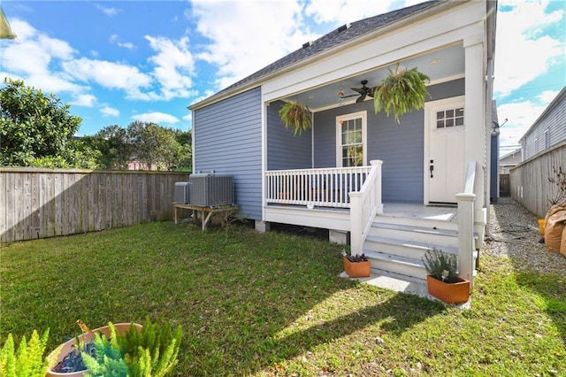 property entrance with a yard, fence, central AC, and ceiling fan