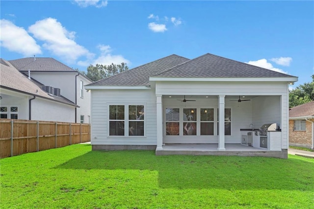 rear view of house featuring a patio, fence, a yard, a shingled roof, and ceiling fan