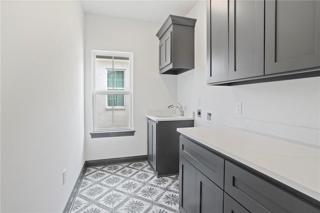 laundry room featuring hookup for a washing machine, light floors, baseboards, cabinet space, and a sink