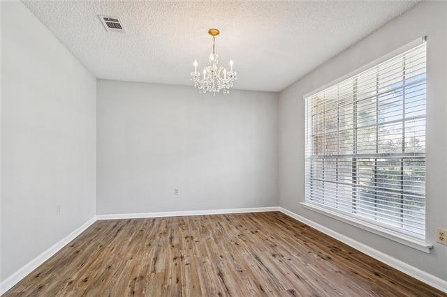 empty room with a chandelier, baseboards, and wood finished floors