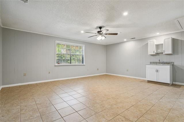 unfurnished living room featuring baseboards, attic access, light tile patterned flooring, ceiling fan, and a textured ceiling