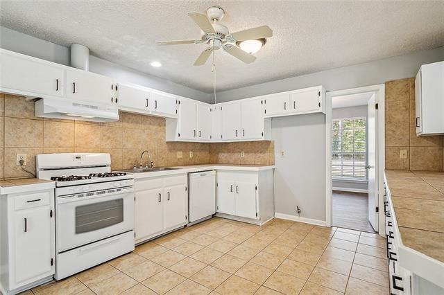 kitchen featuring white cabinetry, white appliances, under cabinet range hood, and a sink