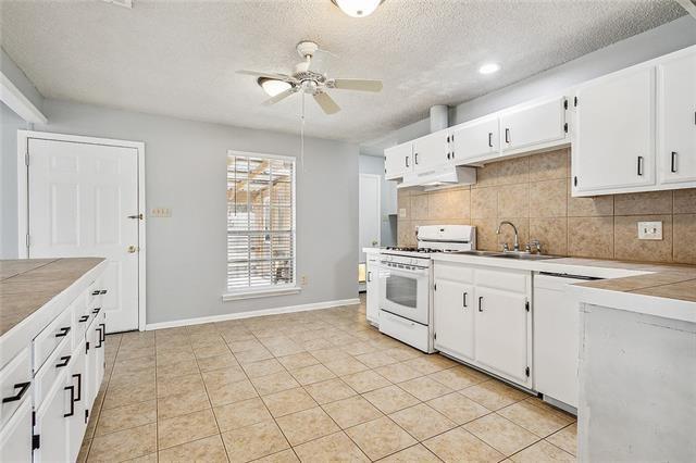 kitchen with dishwashing machine, a ceiling fan, white range with gas stovetop, light countertops, and backsplash