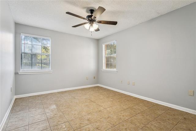 empty room featuring light tile patterned floors, baseboards, a textured ceiling, and ceiling fan