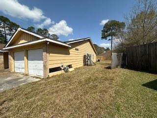 view of home's exterior with a yard, a garage, and fence