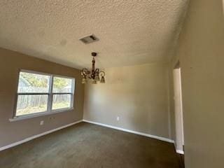 unfurnished dining area with baseboards, visible vents, a textured ceiling, a notable chandelier, and dark carpet