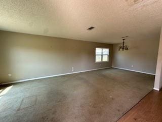 spare room with a notable chandelier, a textured ceiling, and baseboards