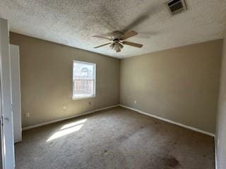 spare room featuring a textured ceiling, carpet flooring, visible vents, and ceiling fan