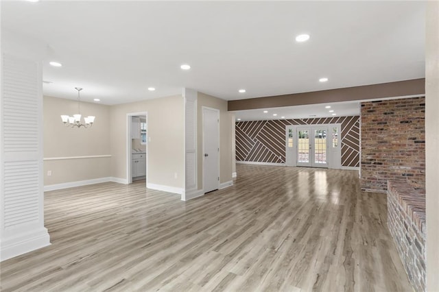 unfurnished living room with baseboards, light wood-type flooring, recessed lighting, french doors, and a notable chandelier