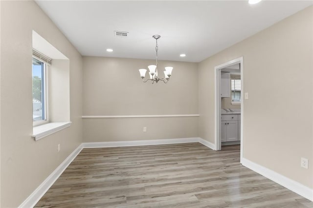 unfurnished dining area featuring light wood-type flooring, visible vents, baseboards, and a healthy amount of sunlight