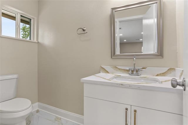 bathroom with vanity, toilet, baseboards, and marble finish floor