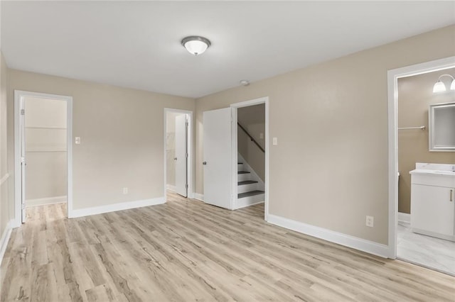 spare room featuring baseboards, light wood-style floors, and stairs