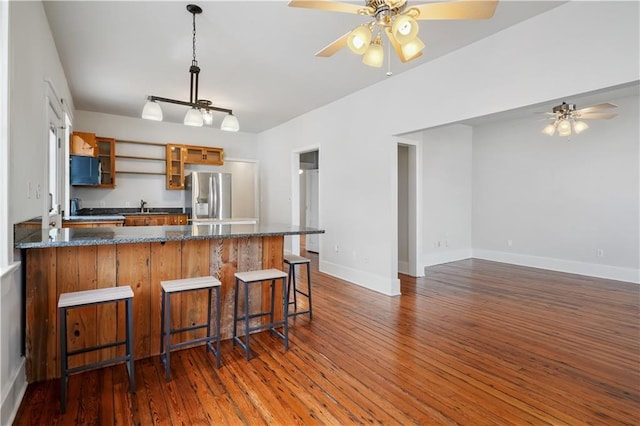 kitchen featuring glass insert cabinets, a peninsula, stainless steel refrigerator with ice dispenser, dark wood-style floors, and a sink