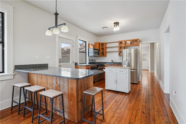 kitchen featuring hardwood / wood-style flooring, a peninsula, visible vents, and stainless steel appliances