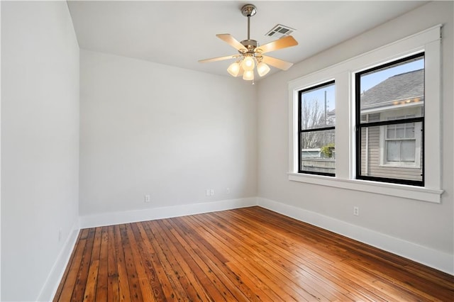 spare room featuring hardwood / wood-style flooring, visible vents, and baseboards