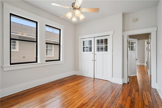 unfurnished bedroom with hardwood / wood-style floors, baseboards, a closet, and ceiling fan