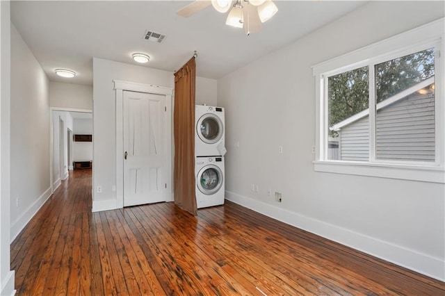 laundry area with visible vents, baseboards, dark wood-style floors, and stacked washing maching and dryer