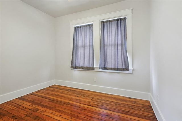 unfurnished room with baseboards and wood-type flooring