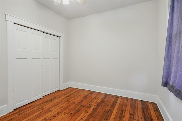 unfurnished bedroom featuring hardwood / wood-style flooring, a ceiling fan, baseboards, and a closet