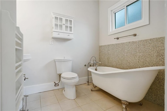 full bath with tile patterned flooring, a freestanding tub, toilet, and baseboards