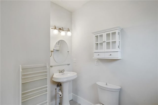 half bathroom featuring a sink, baseboards, and toilet