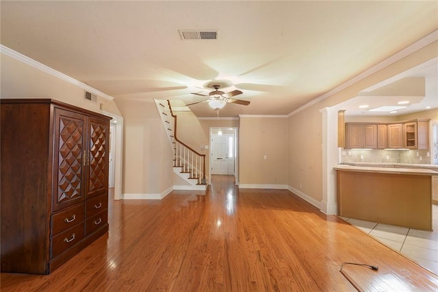 unfurnished living room with visible vents, crown molding, baseboards, stairs, and light wood-style flooring