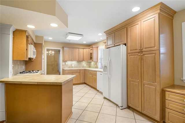 kitchen featuring backsplash, a peninsula, light tile patterned flooring, white appliances, and a sink